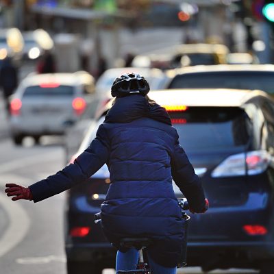 Winter city scene. Woman on bike in traffic